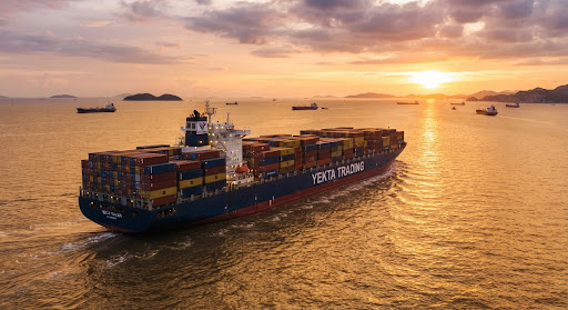 Ultra large container carrier ship cruising along maritime trade route at sunset carrying thousands of containers with golden reflections on the sea
